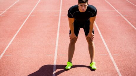 Tired athlete standing on running track